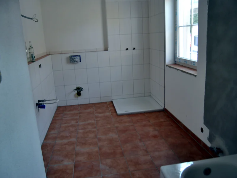 Bad im Rohbau mit fertig verlegtem Boden und vorbereiteten Wandanschlüssen