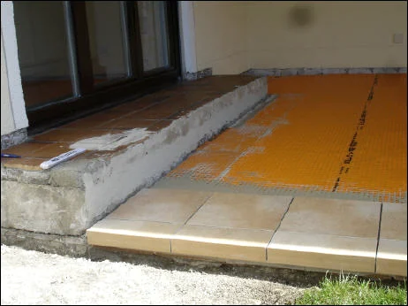 Terrassenaufbau mit orangefarbener Entkopplungsmatte vor dem Verlegen